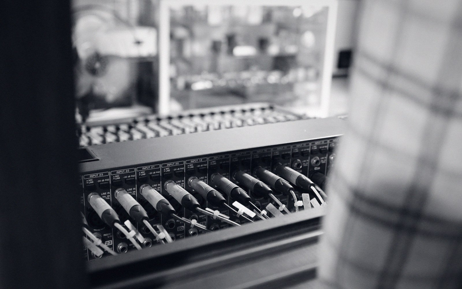 A patchbay panel close-up, patch cables inserted in several points, against the rack panel's brushed-metal surface